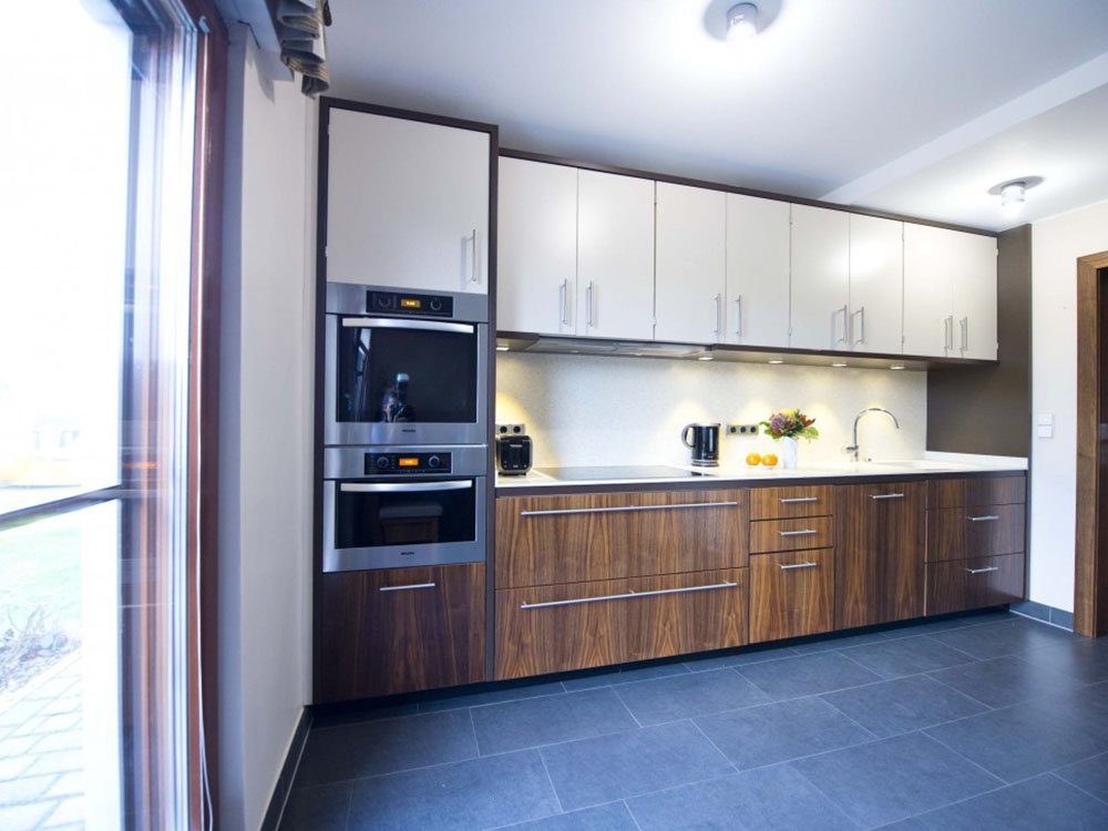 Küchenmöbel nach Maß – moderne Einbauküche | Tischlerei Bexter Moderne Einbauküche mit Holzfronten, weißen Oberschränken und Einbaugeräten